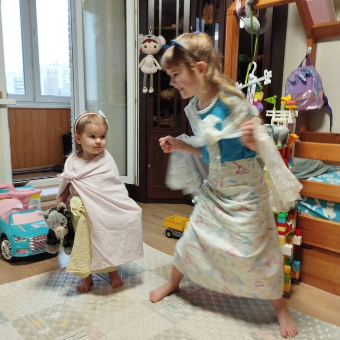 Две радостные маленькие девочки дурачатся. Переоделись в принцесс, обмотавшись 
                детскими пелёнками. Обстановка - квартира.
